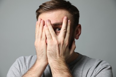 Young man feeling fear on grey background