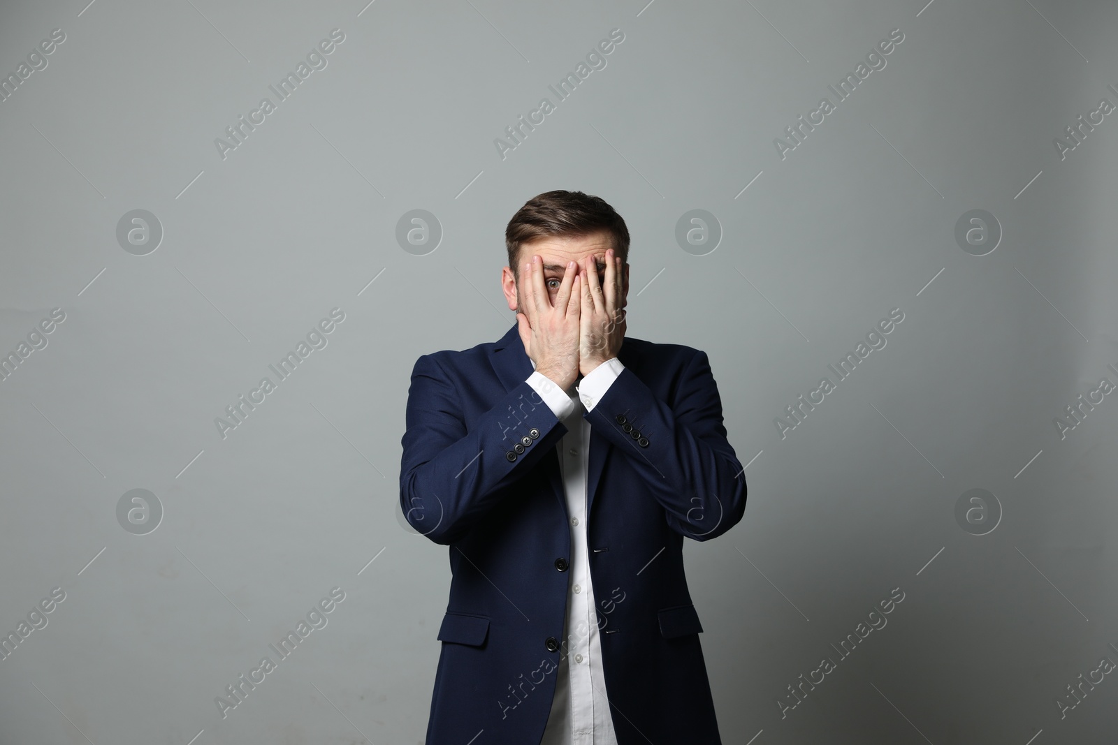 Photo of Young businessman feeling fear on grey background