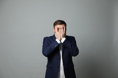 Photo of Young businessman feeling fear on grey background