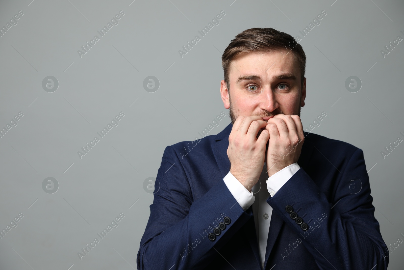 Photo of Young businessman feeling fear on grey background. Space for text