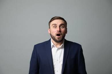 Young businessman feeling fear on grey background