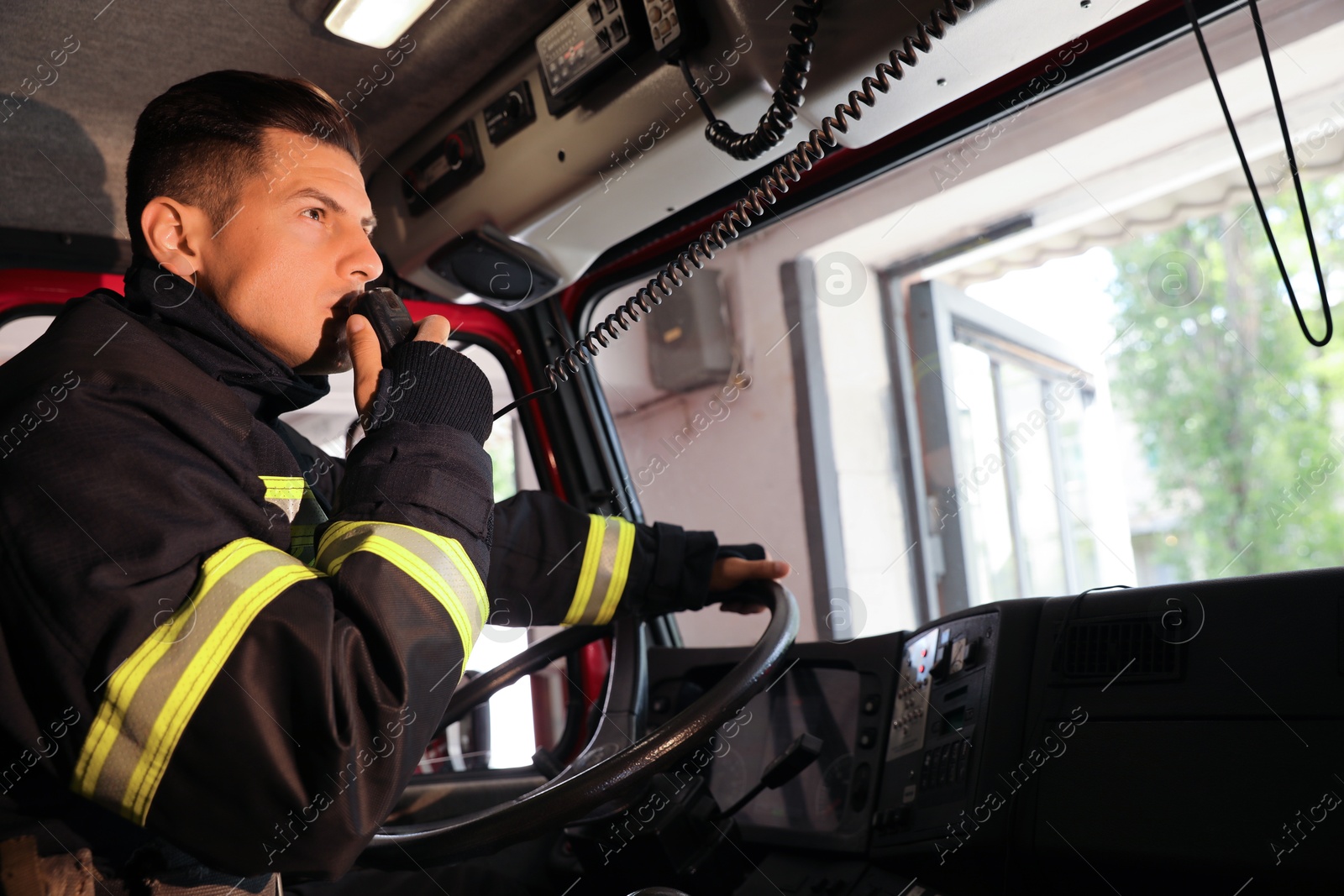 Photo of Firefighter using radio set while driving fire truck, space for text