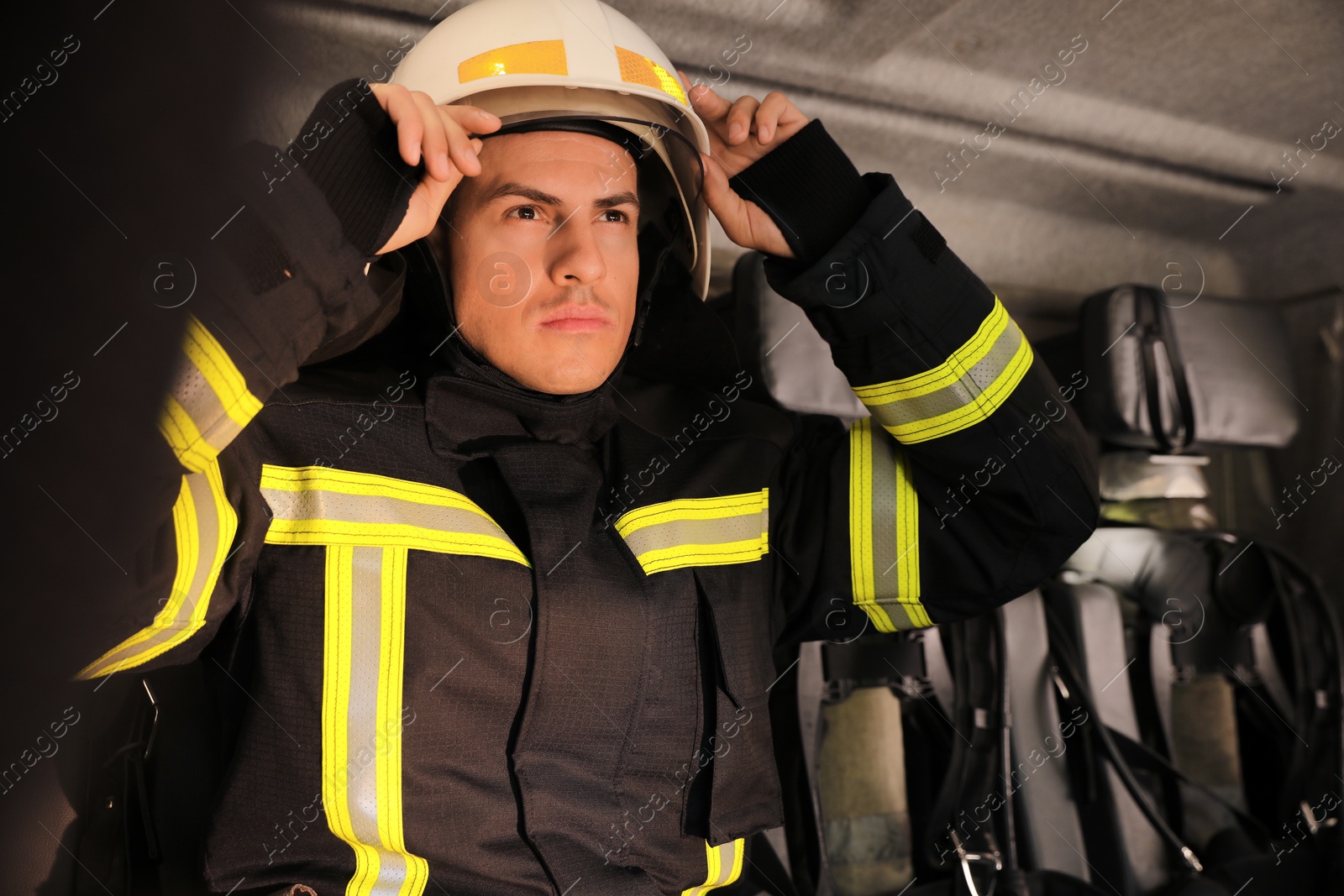 Photo of Firefighter in uniform on backseat of fire truck