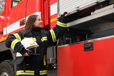 Portrait of firefighter in uniform with helmet near fire truck outdoors