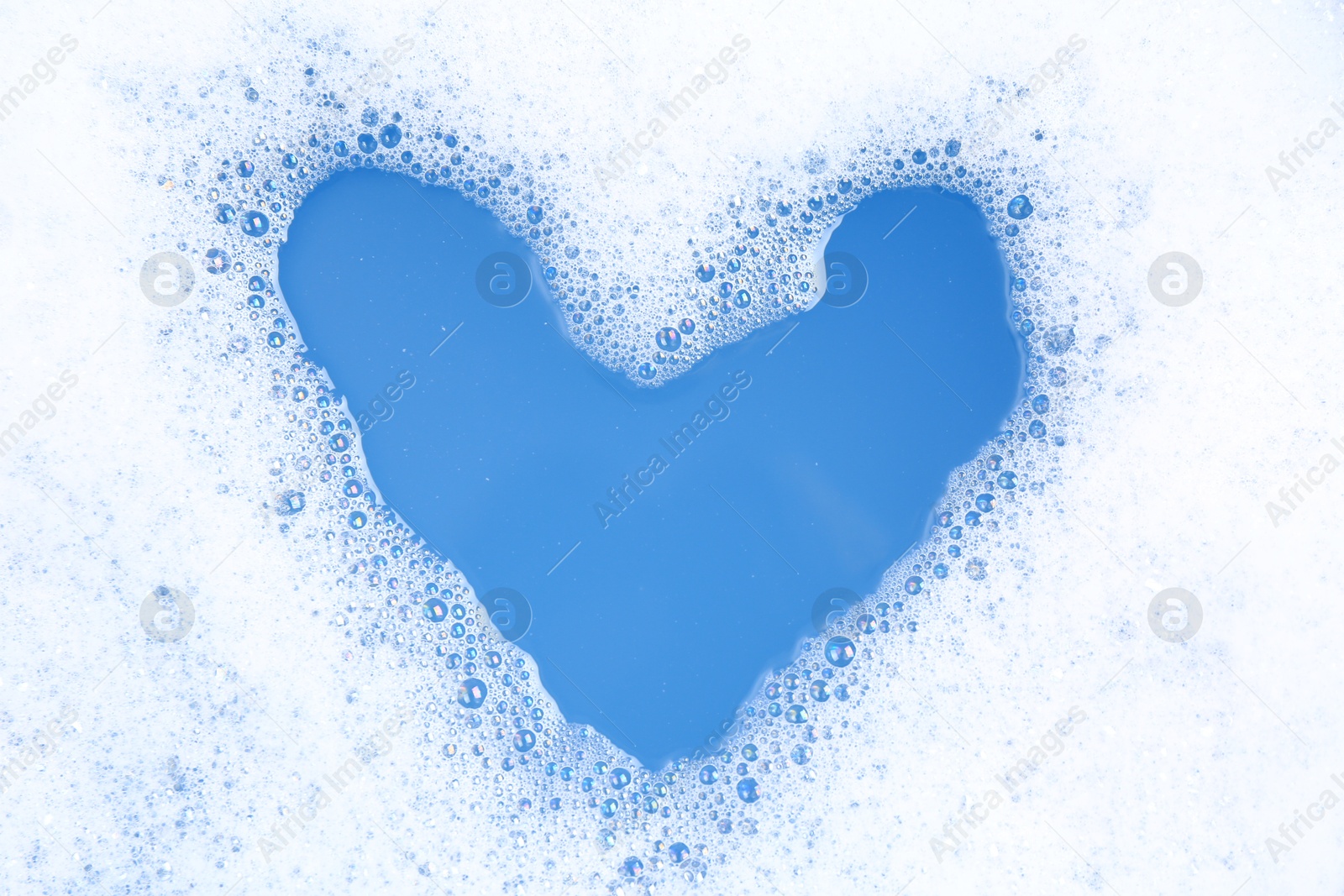 Photo of Heart shape made of detergent foam in water, top view. Hand washing laundry