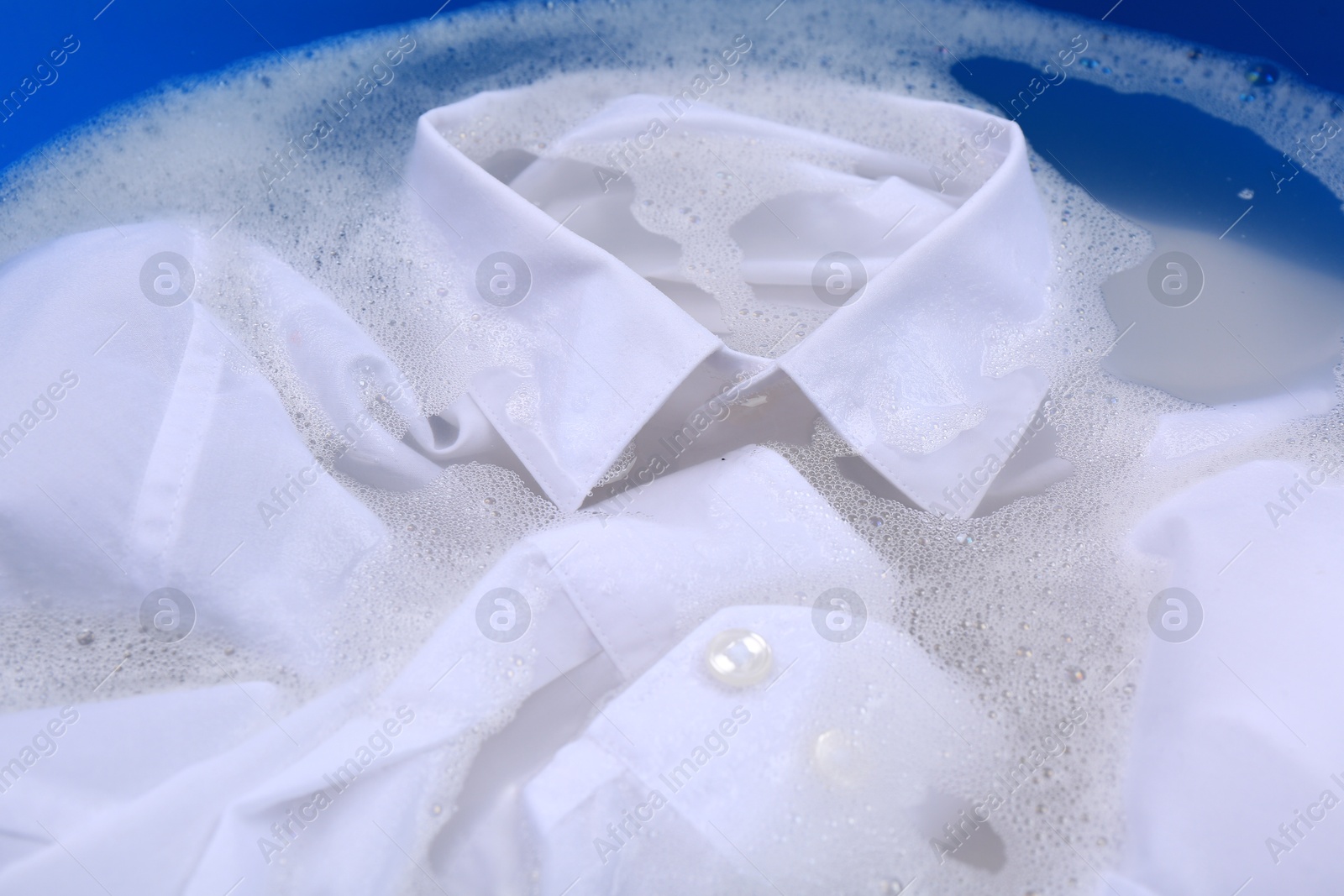 Photo of White shirt in suds, closeup. Hand washing laundry