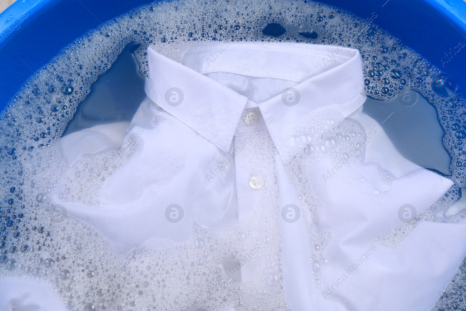 Photo of White shirt in suds, closeup. Hand washing laundry