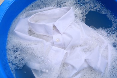 Photo of White shirt in suds, closeup. Hand washing laundry