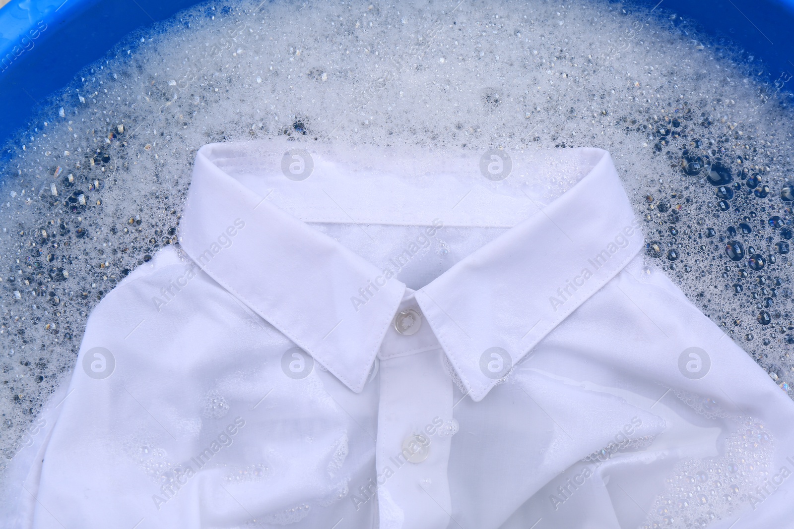 Photo of White shirt in suds, closeup. Hand washing laundry