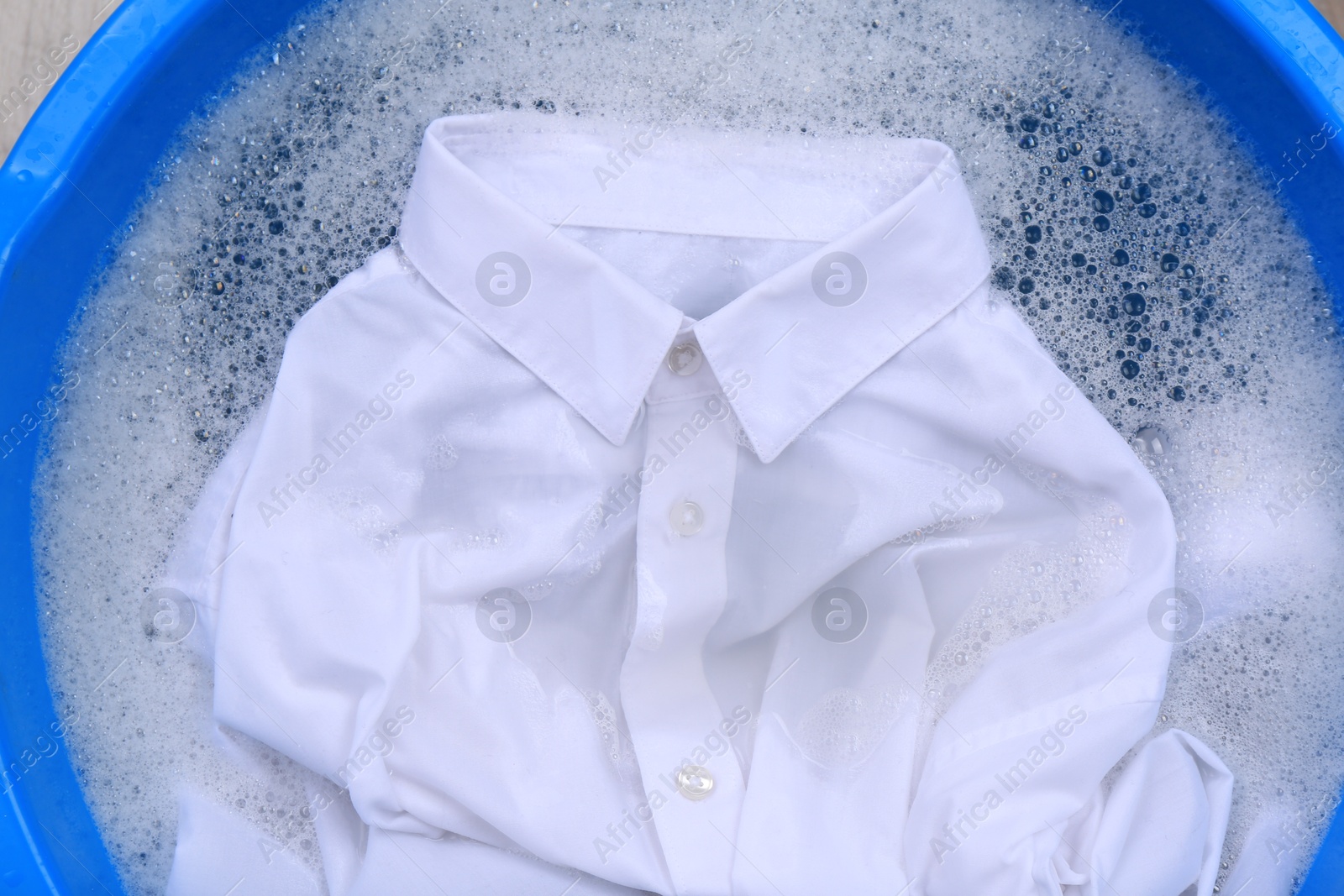 Photo of White shirt in suds, closeup. Hand washing laundry