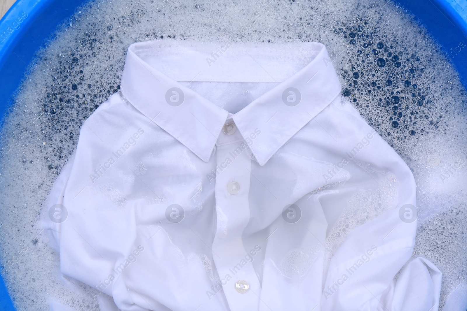 Photo of White shirt in suds, closeup. Hand washing laundry