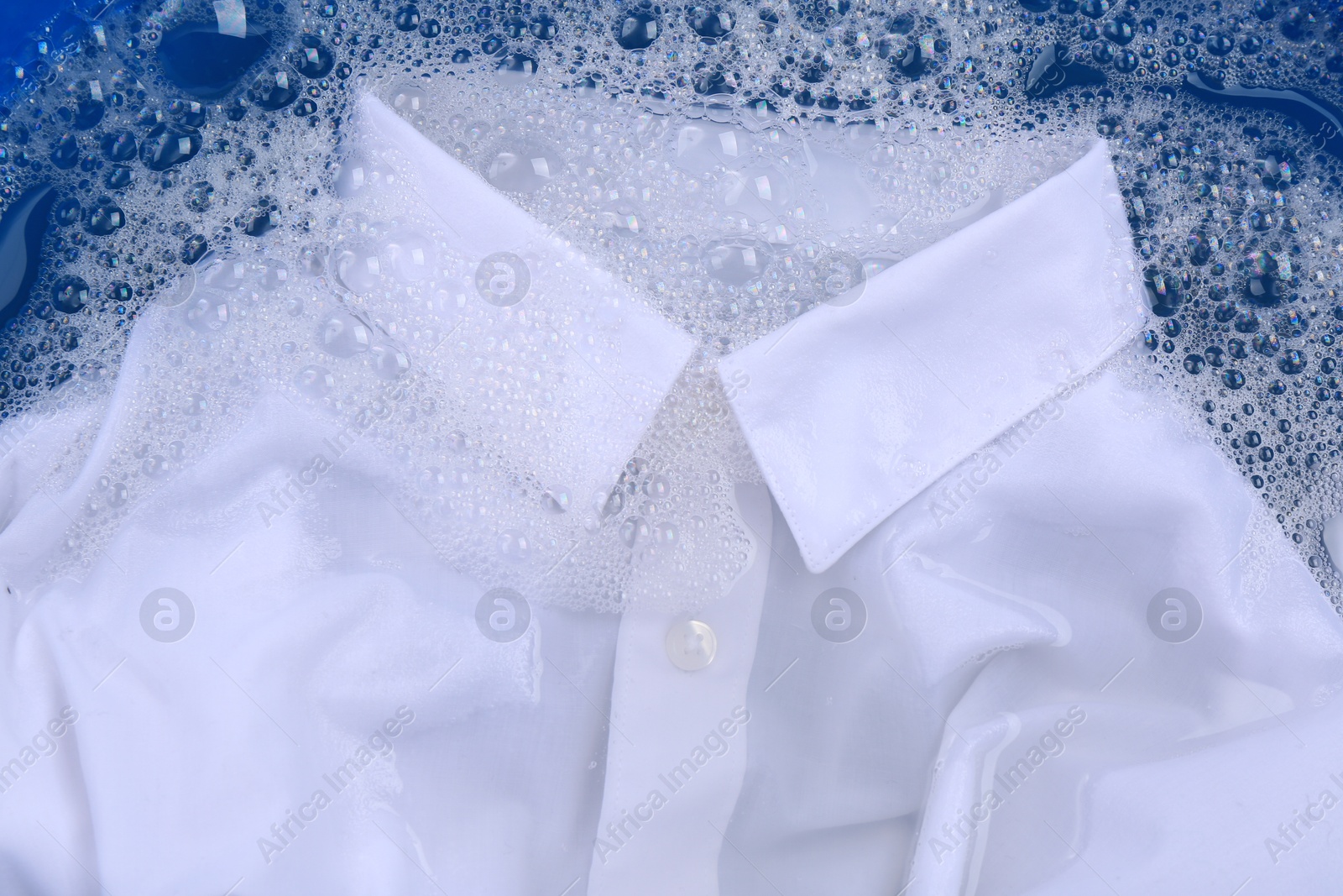 Photo of White shirt in suds, closeup. Hand washing laundry