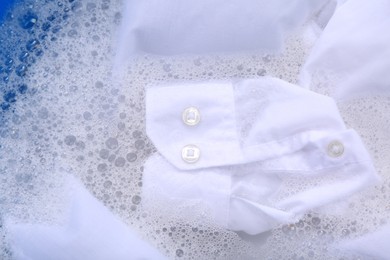 Photo of White garment in suds, closeup. Hand washing laundry