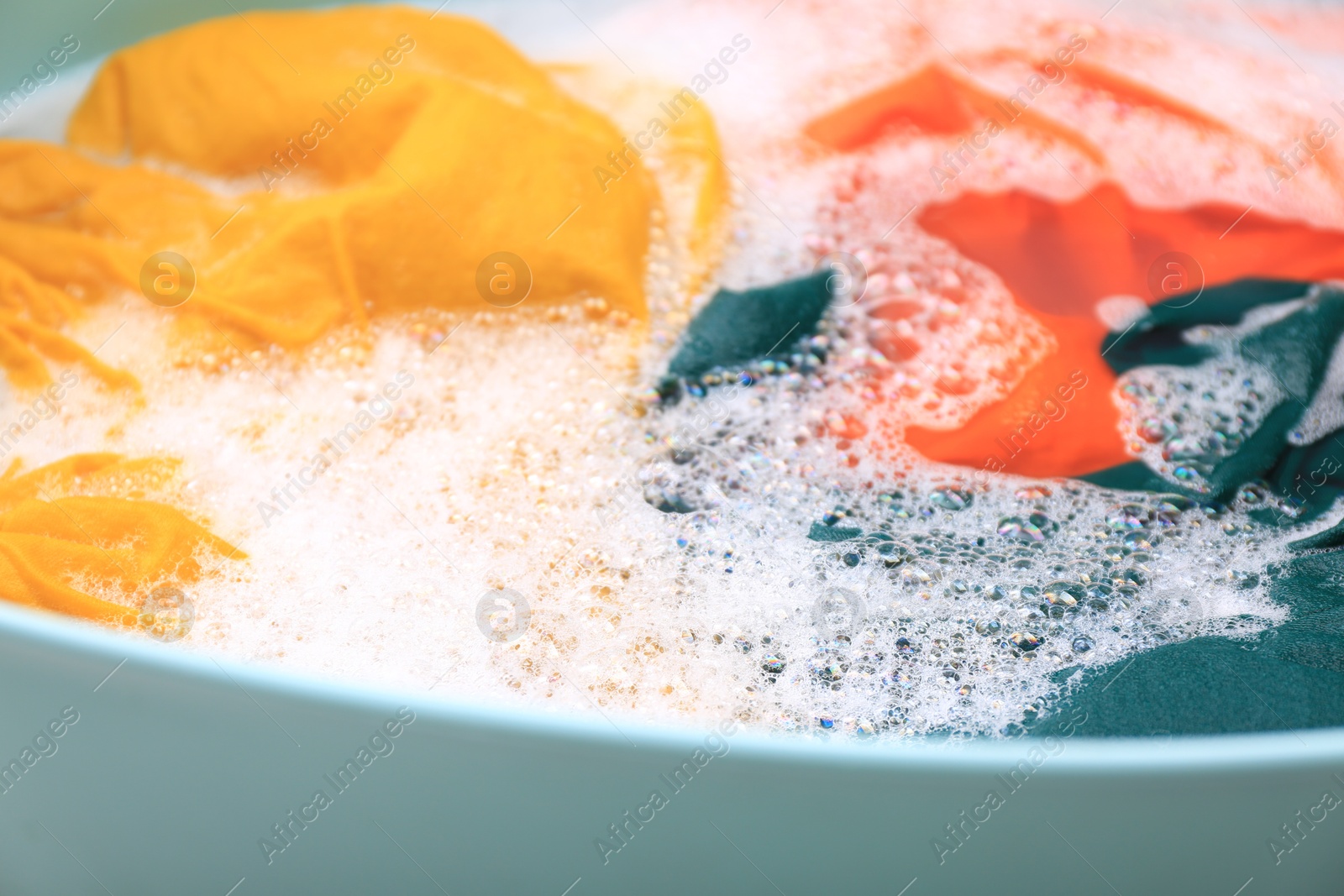 Photo of Basin with colorful clothes in suds, closeup. Hand washing laundry