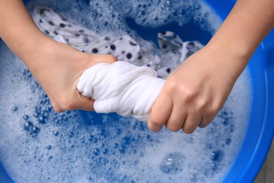 Photo of Woman wringing garment over basin, closeup. Hand washing laundry