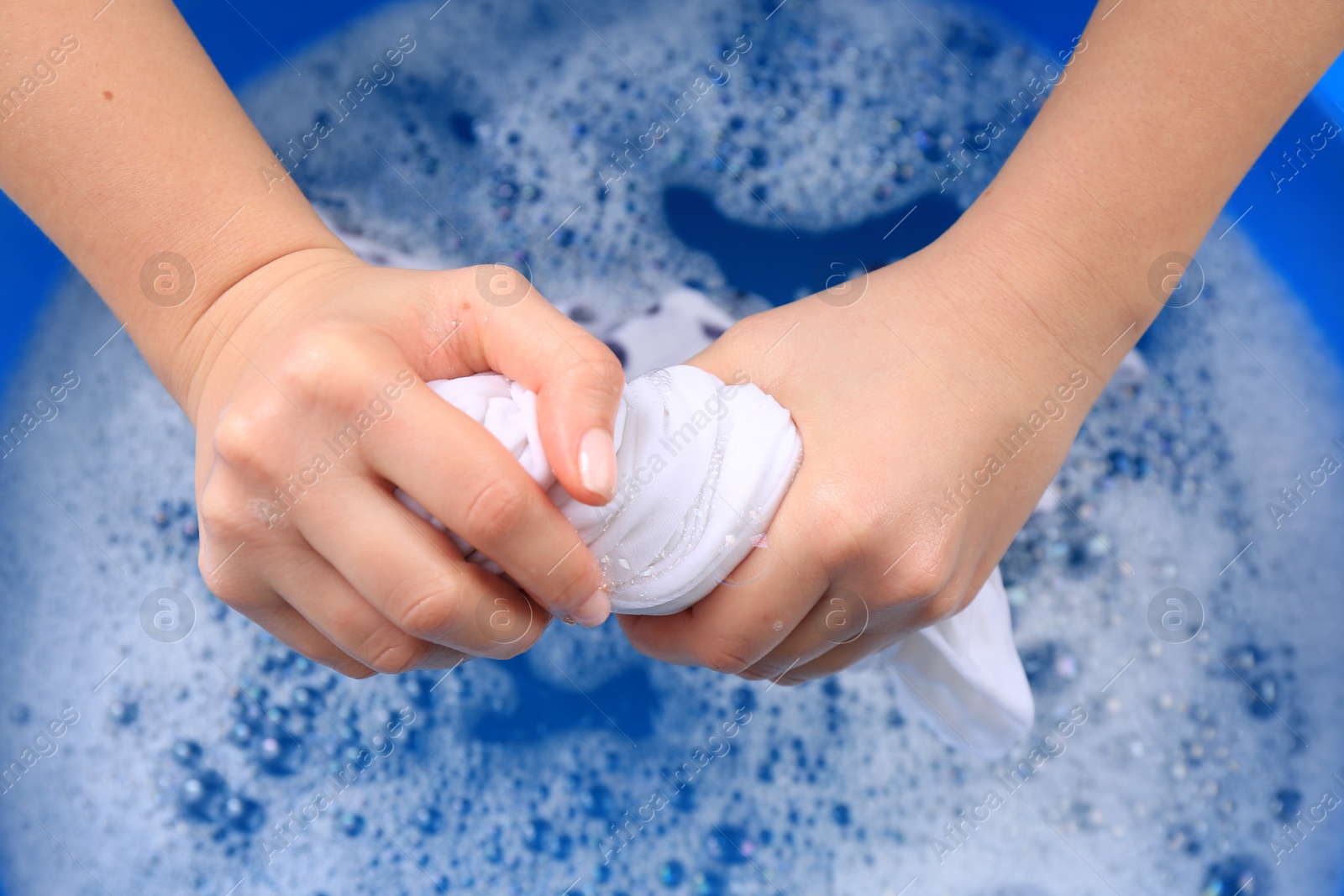 Photo of Woman wringing garment over basin, closeup. Hand washing laundry