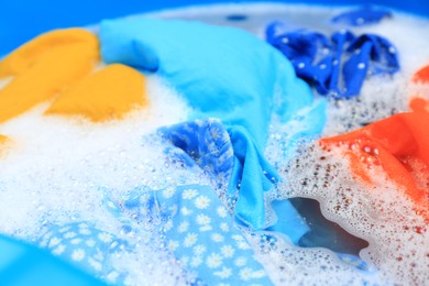 Photo of Colorful clothes in suds, closeup. Hand washing laundry