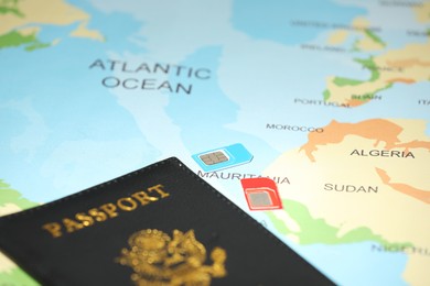 Modern SIM cards and passport on world map, closeup