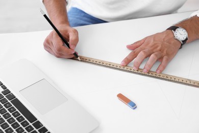 Photo of Architect making engineering drawing at table in office, closeup