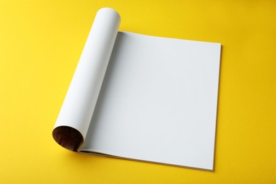 Photo of Open magazine with blank page on yellow background. Mockup for design