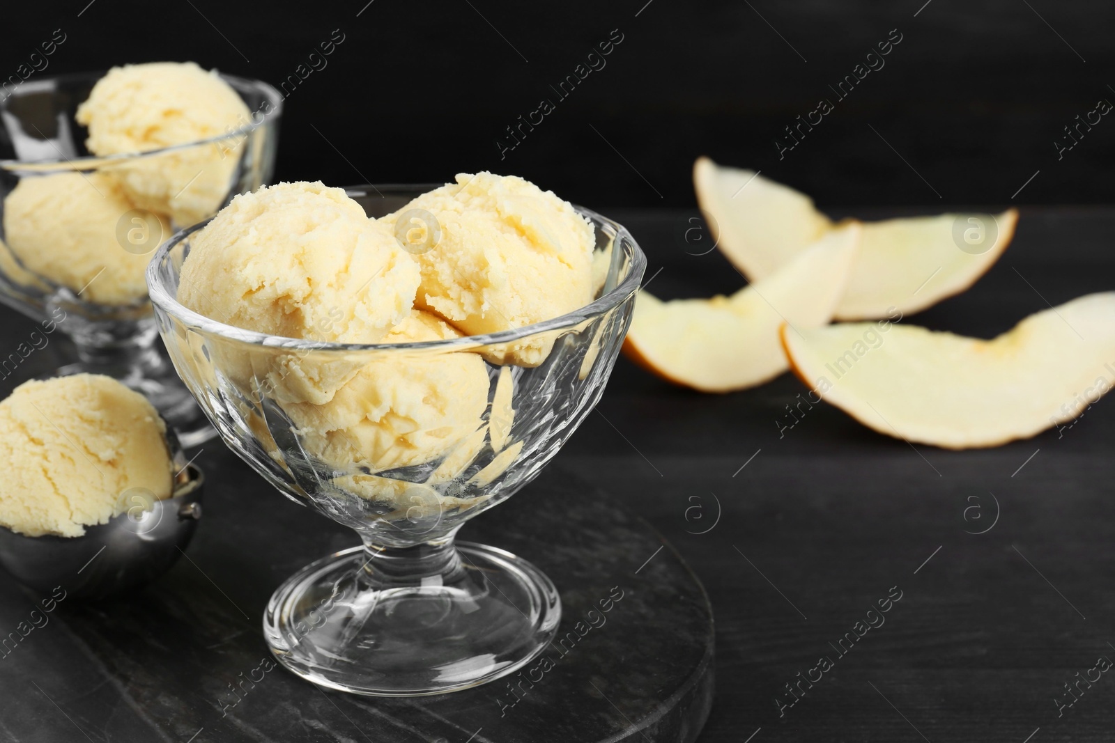 Photo of Scoops of melon sorbet in glass dessert bowls on dark wooden table, closeup