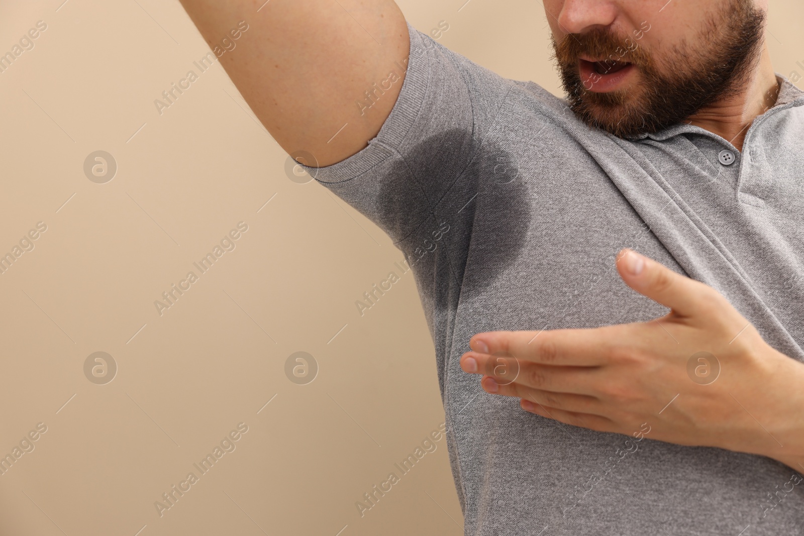 Photo of Man in t-shirt before using deodorant on beige background, closeup. Space for text