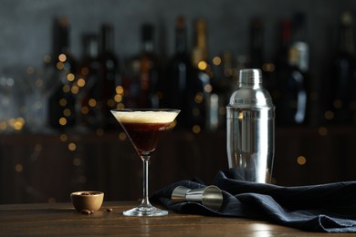 Refreshing cocktail, shaker, jigger and coffee beans on wooden table