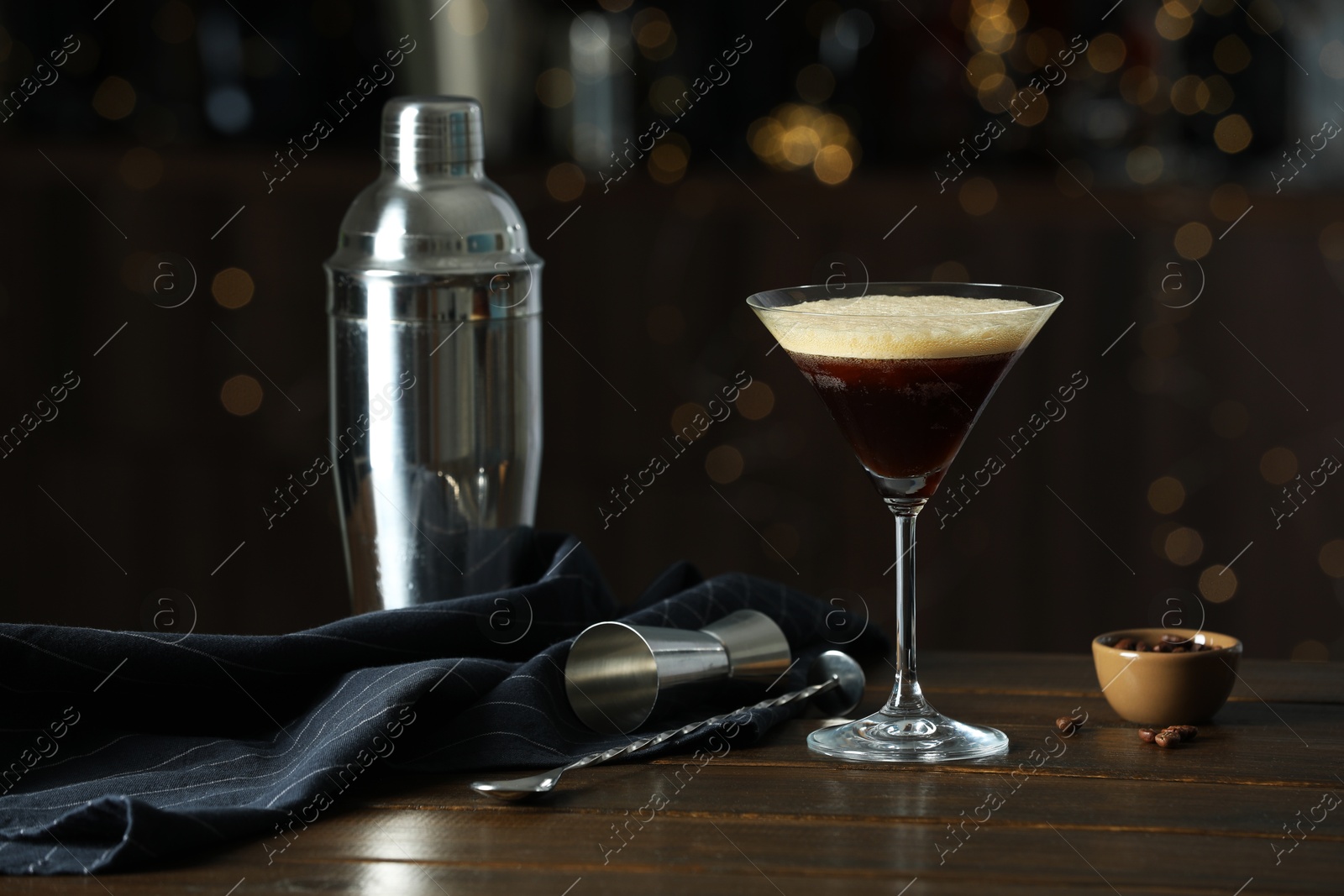 Photo of Refreshing cocktail, shaker, jigger, spoon and coffee beans on wooden table