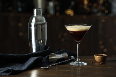 Refreshing cocktail, shaker, jigger, spoon and coffee beans on wooden table