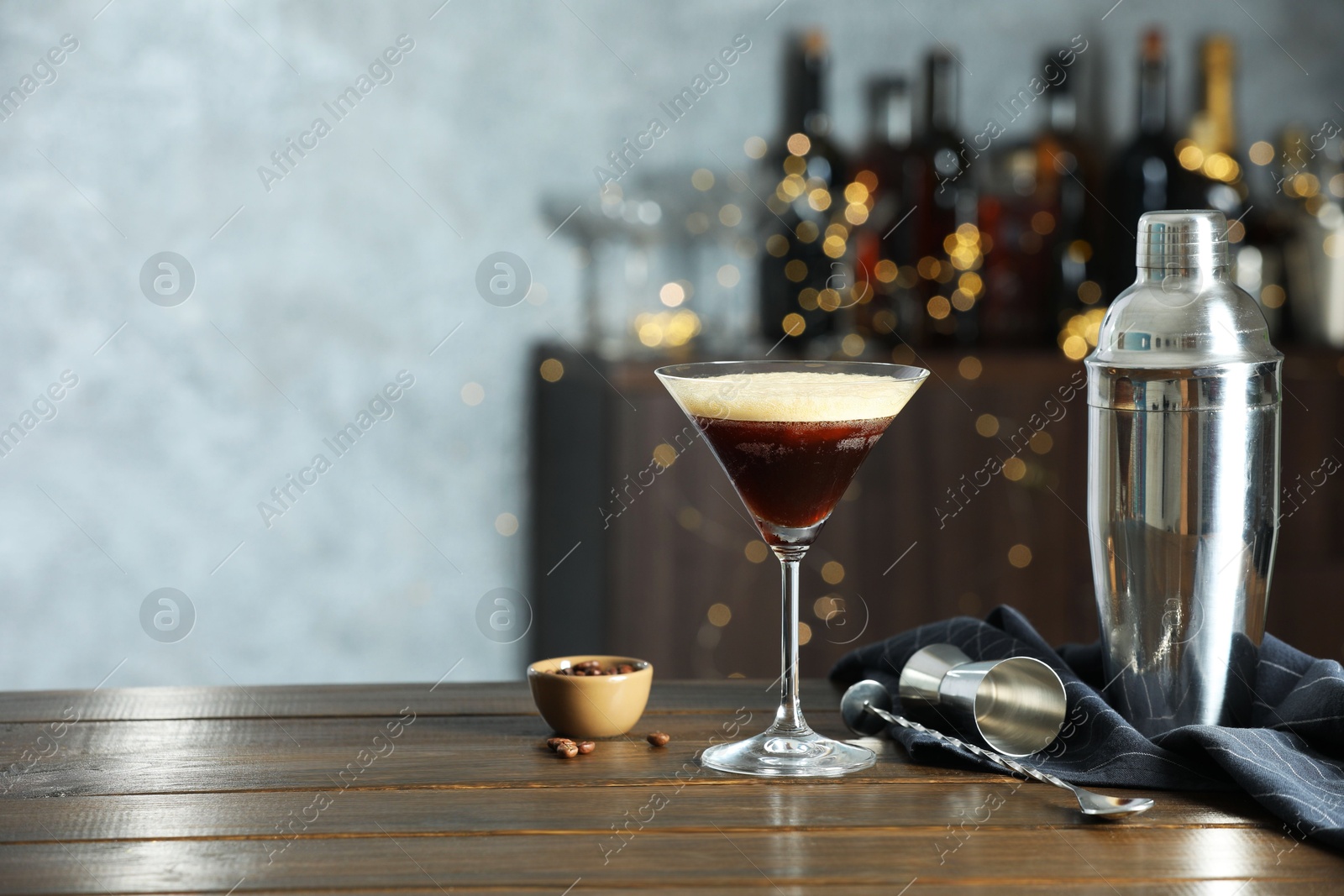 Photo of Refreshing cocktail, shaker, jigger, spoon and coffee beans on wooden table. Space for text