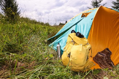 Photo of Tent, backpack, binoculars and shoes on green grass outdoors, space for text