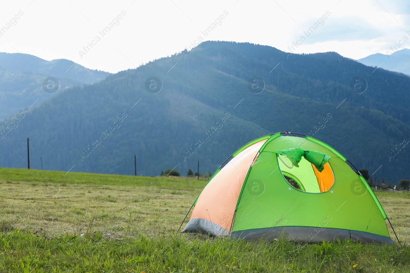 Photo of Tent on green grass in mountains, space for text