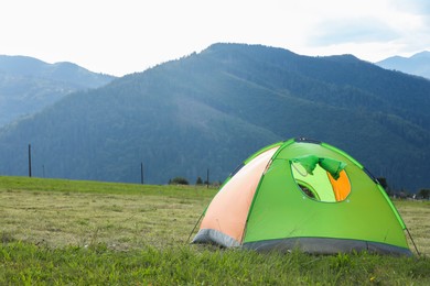 Photo of Tent on green grass in mountains, space for text