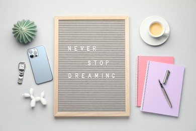 Photo of Flat lay composition of letter board with phrase Never Stop Dreaming on light table