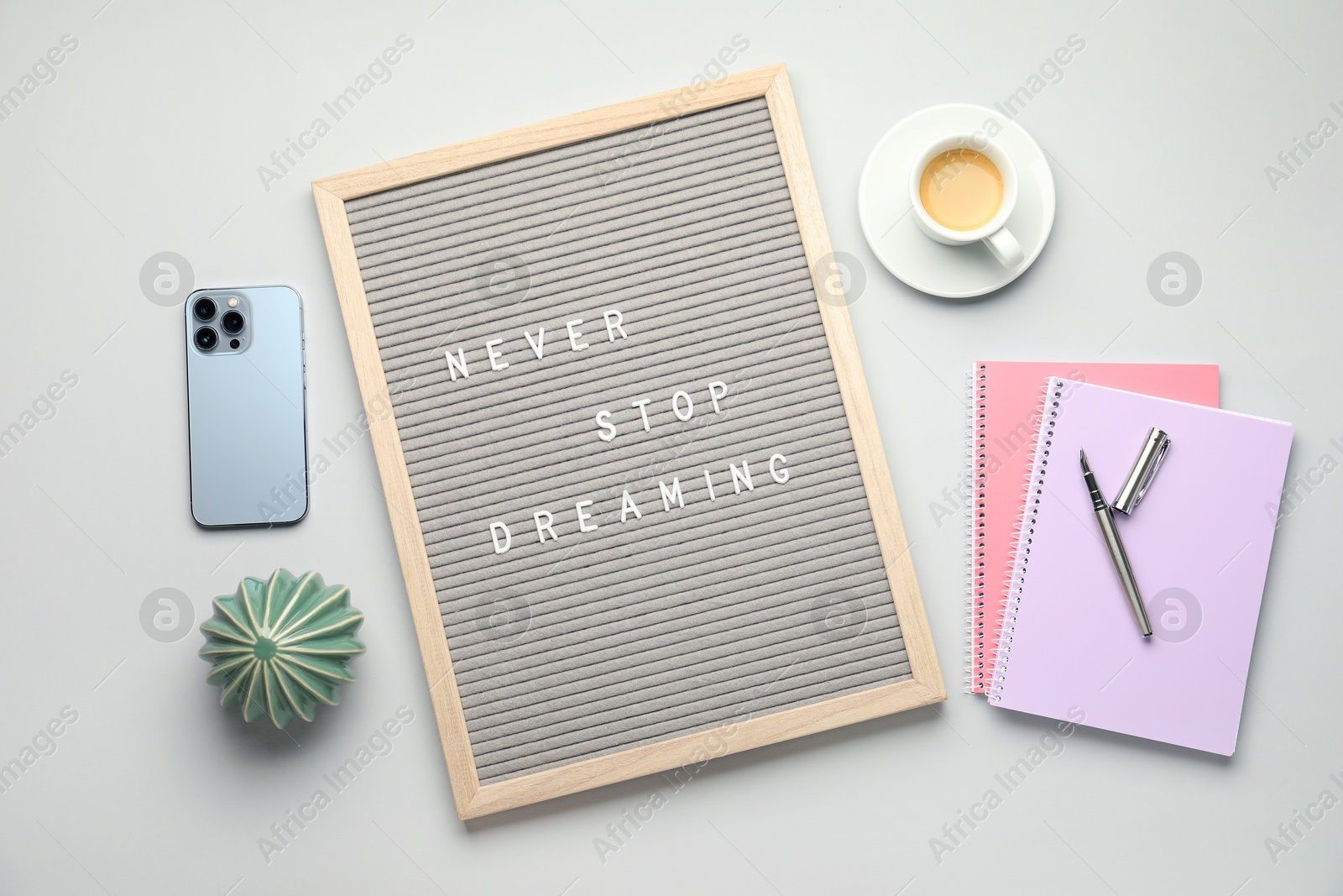 Photo of Flat lay composition of letter board with phrase Never Stop Dreaming on light table