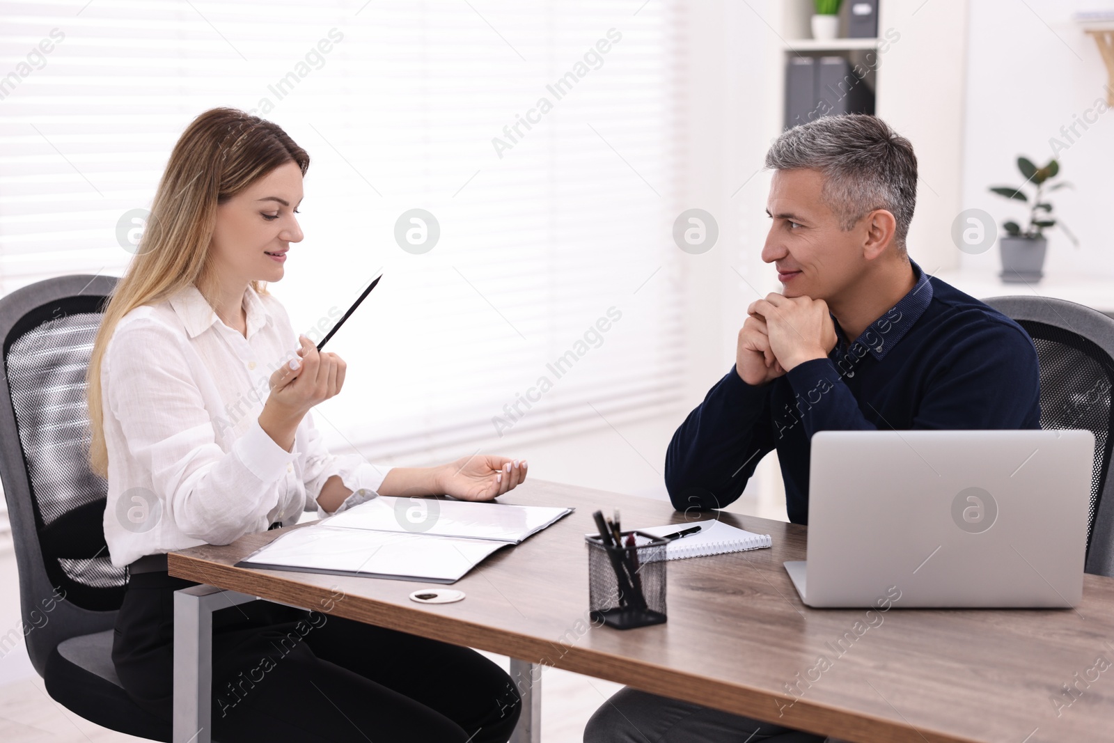 Photo of Banker working with client at wooden table in office