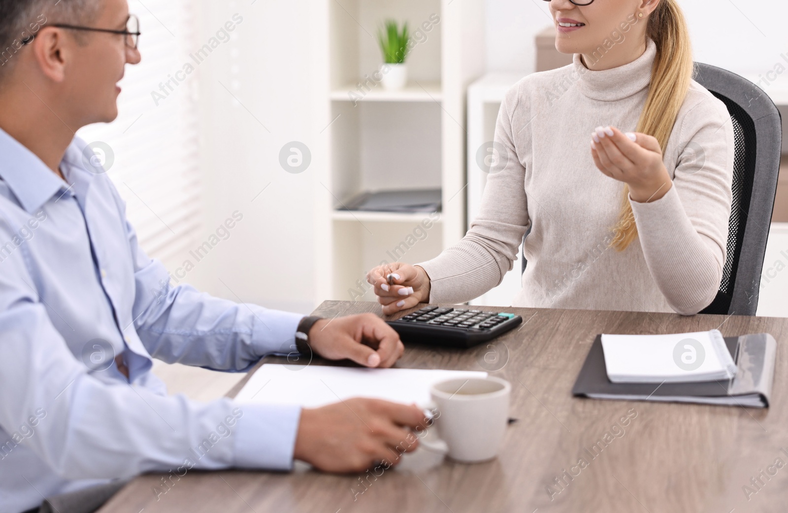 Photo of Banker working with client at table in office