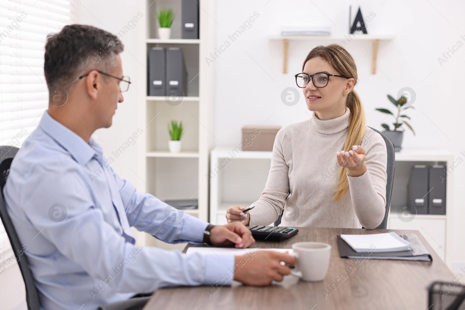 Photo of Banker working with client at table in office