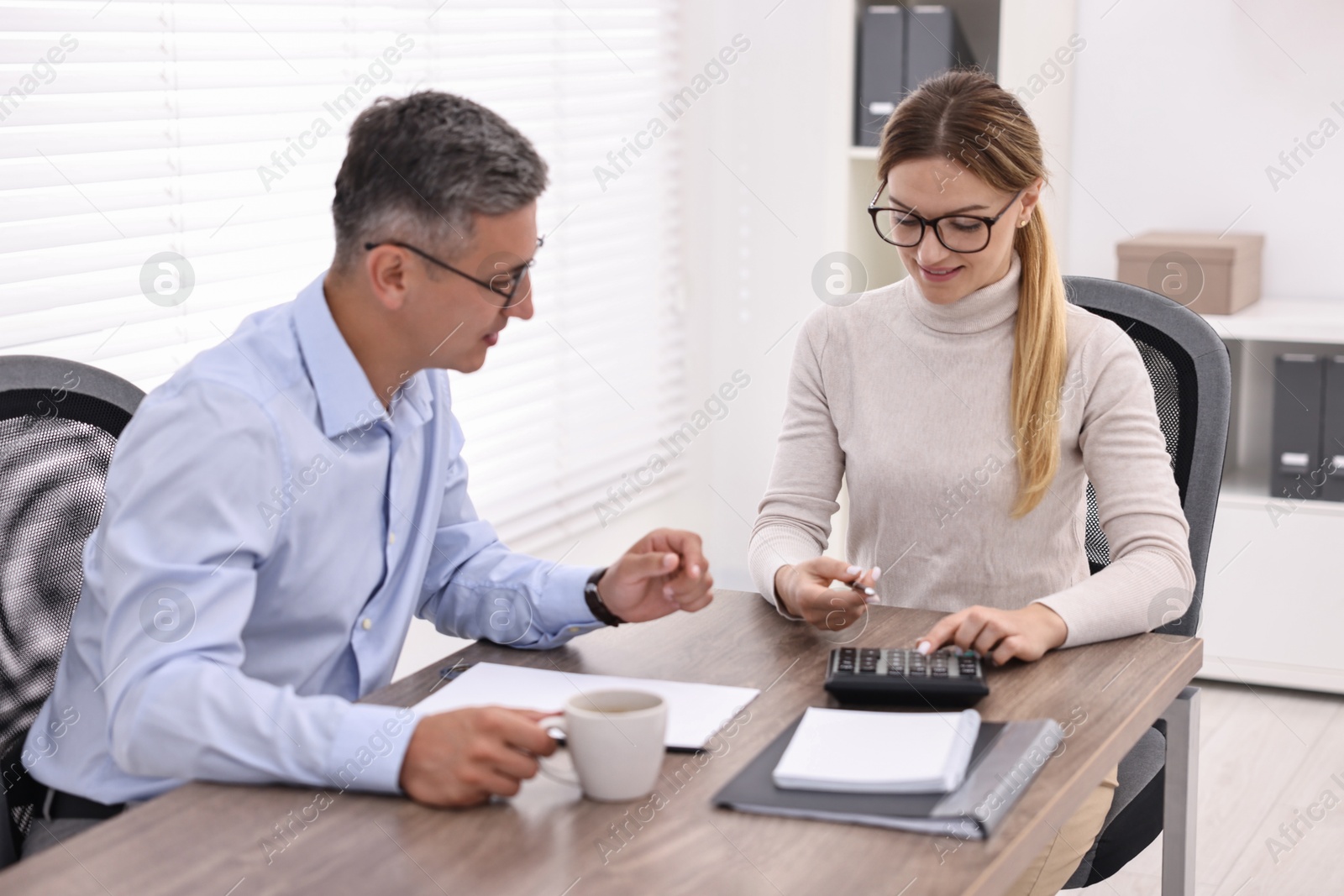 Photo of Banker working with client at table in office