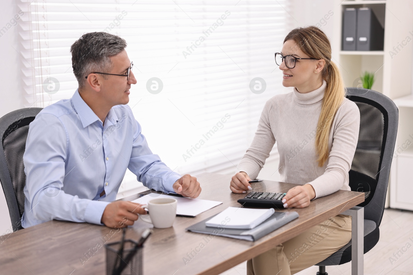 Photo of Banker working with client at table in office