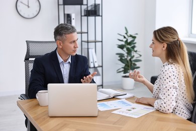 Photo of Banker working with client at wooden table in office