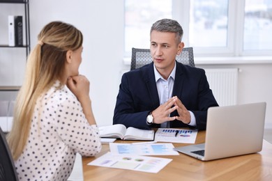 Photo of Banker working with client at wooden table in office