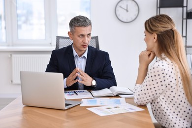 Banker working with client at wooden table in office