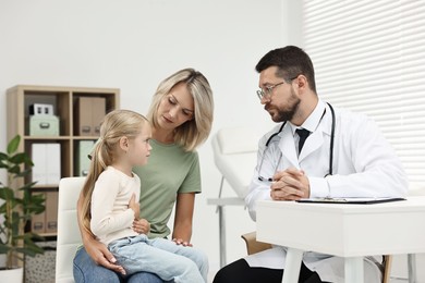 Doctor consulting little girl with stomach pain and her mother in hospital