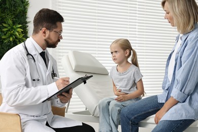 Doctor consulting little girl with stomach pain and her mother in hospital