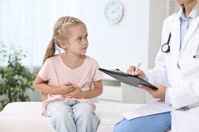 Doctor consulting little girl with stomach pain in hospital, closeup