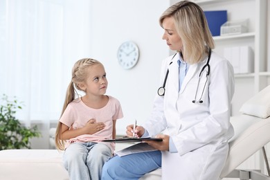 Doctor consulting little girl with stomach pain in hospital