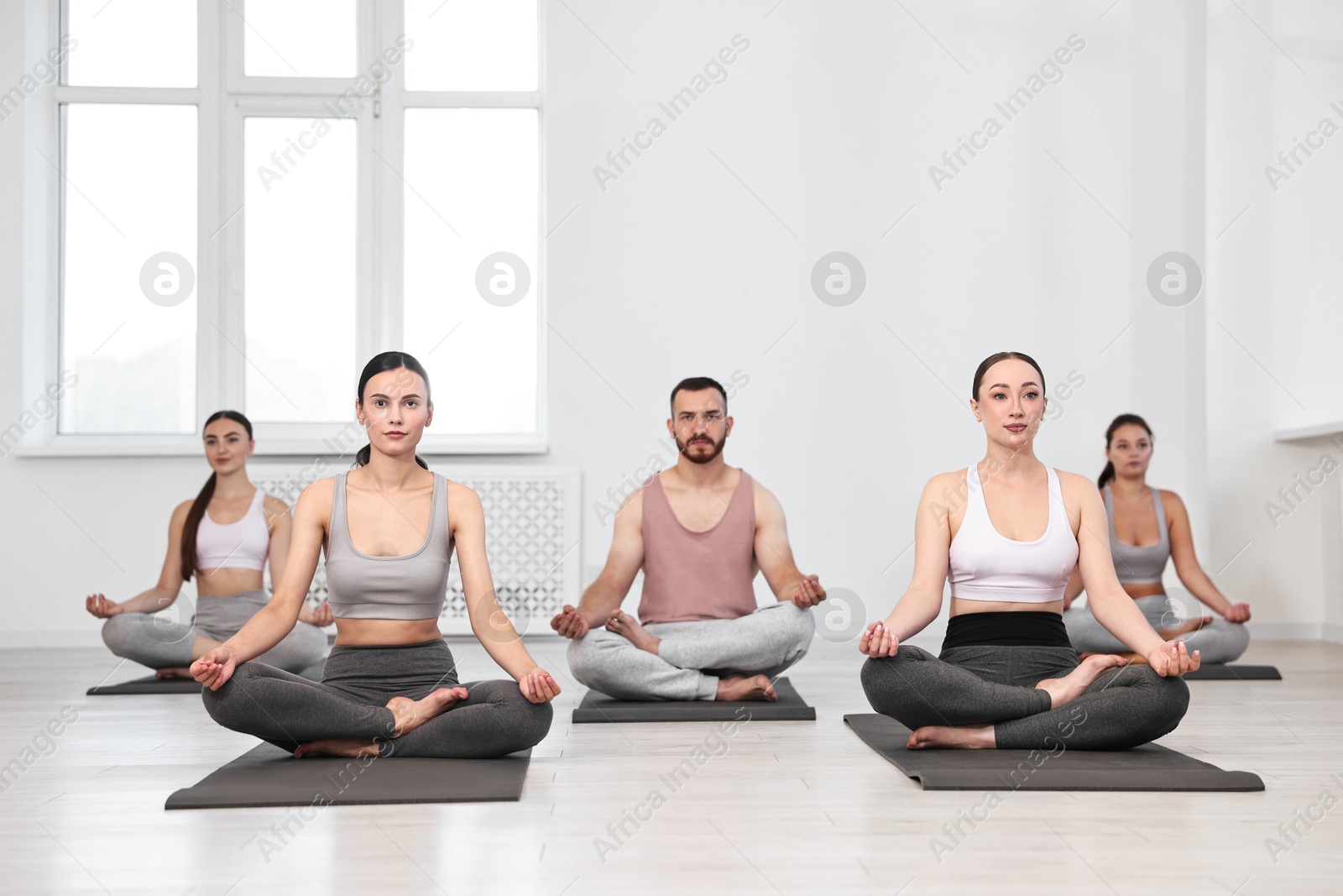 Photo of Group of people meditating on mats in yoga class