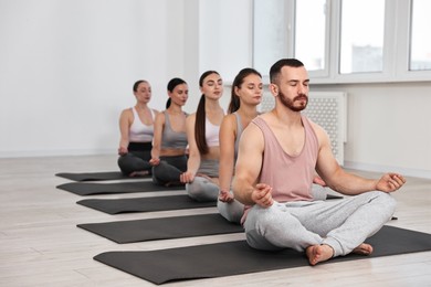 Group of people meditating on mats in yoga class. Space for text