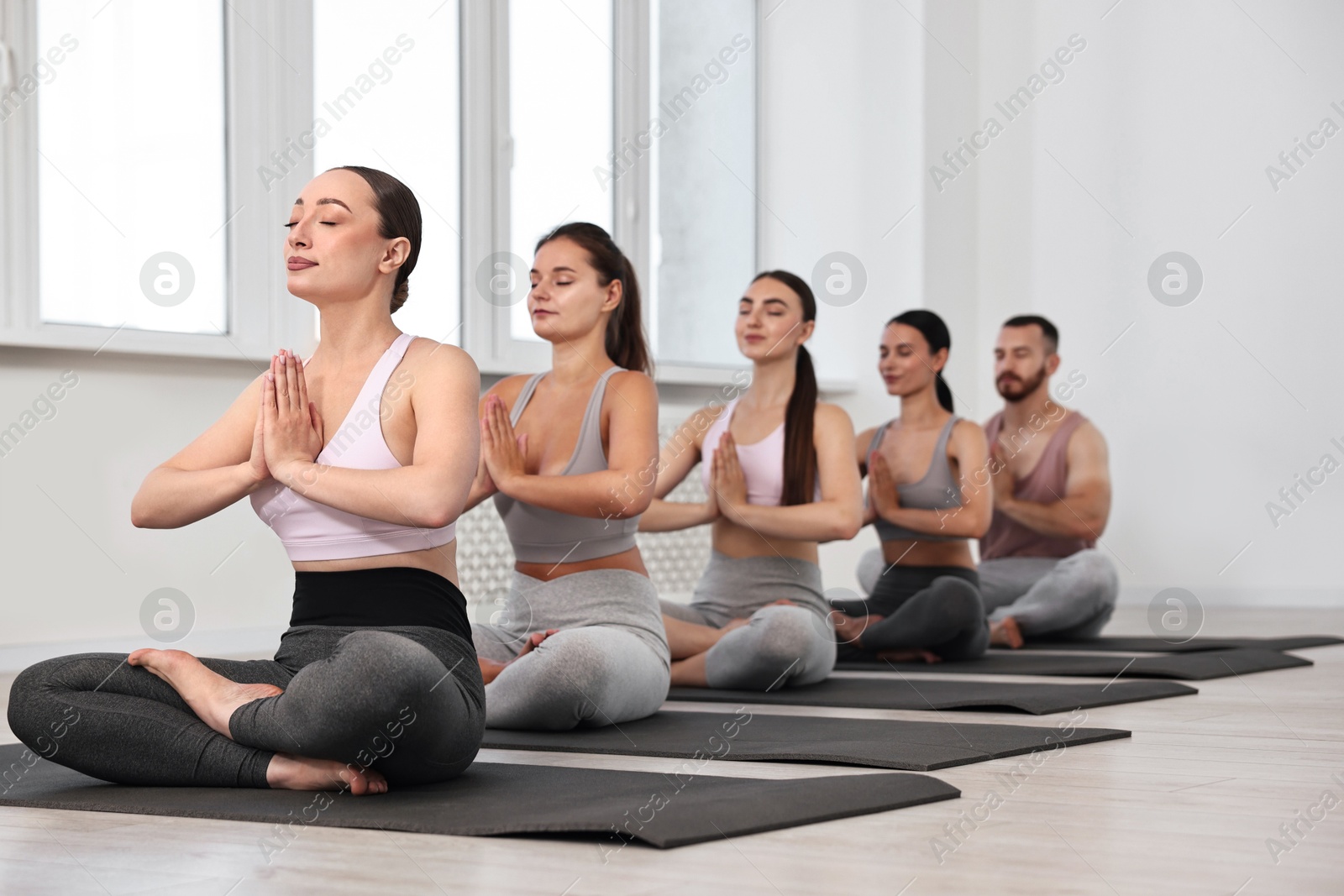 Photo of Group of people meditating on mats in yoga class